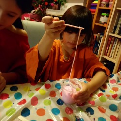 Girl making pink stretchy slime at a party in London