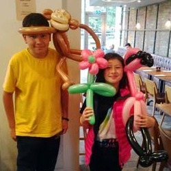 Children holding balloon monkey, flamingo, flower