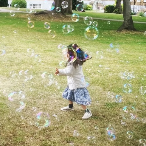 Child surrounded by bubbles in a garden