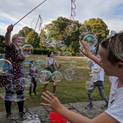 Children chasing bubbles at a park party in London