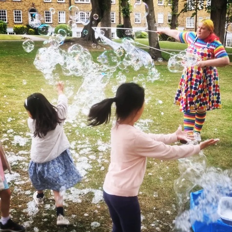 Children playing with foam cloud of bubbles in a garden