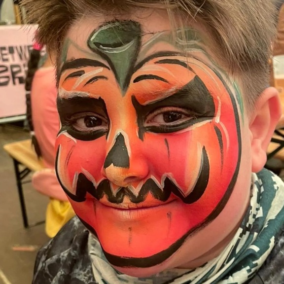 Boy's face painting design of a pumpkin at Halloween party