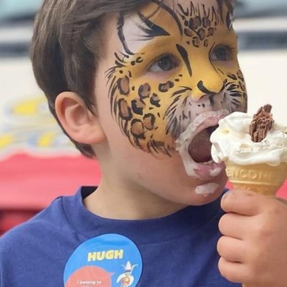 Face painting on boy eating an ice cream, yellow leopard design Face painting on boy eating an ice cream, yellow leopard design