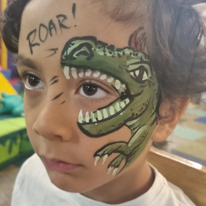 Face paint on boy, green dinosaur with mohawk Face paint on boy, green dinosaur with mohawk