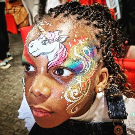 Child with colourful unicorn and rainbow face paint design