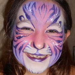 Face painting of a child with a purple tiger and glitter at a party