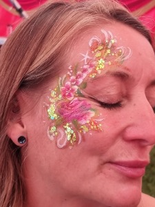 Glitter and glam facepaint design with pink flowers